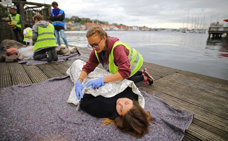 A first aider covers a person at risk of hypothermia with a blanket.